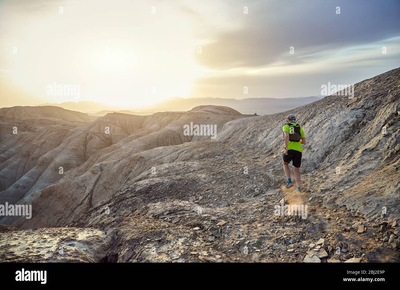 Runner Athlet mit Rucksack auf die wilden Berge in der Wüste bei Sonnenuntergang Stockfoto