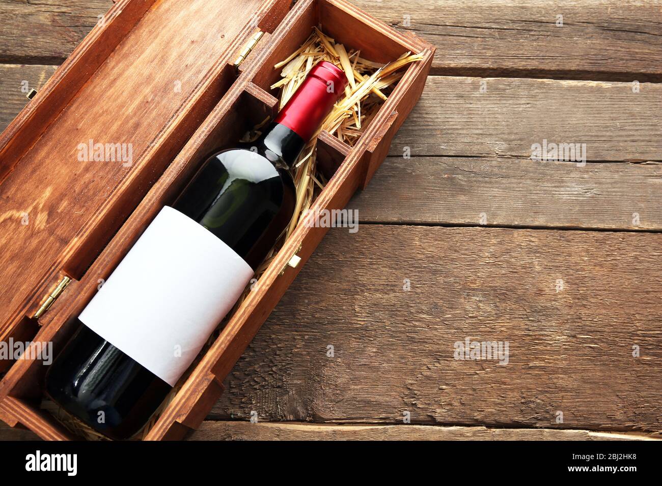 Teurer Wein in elegantem Etui mit Stroh auf Holzhintergrund Stockfoto