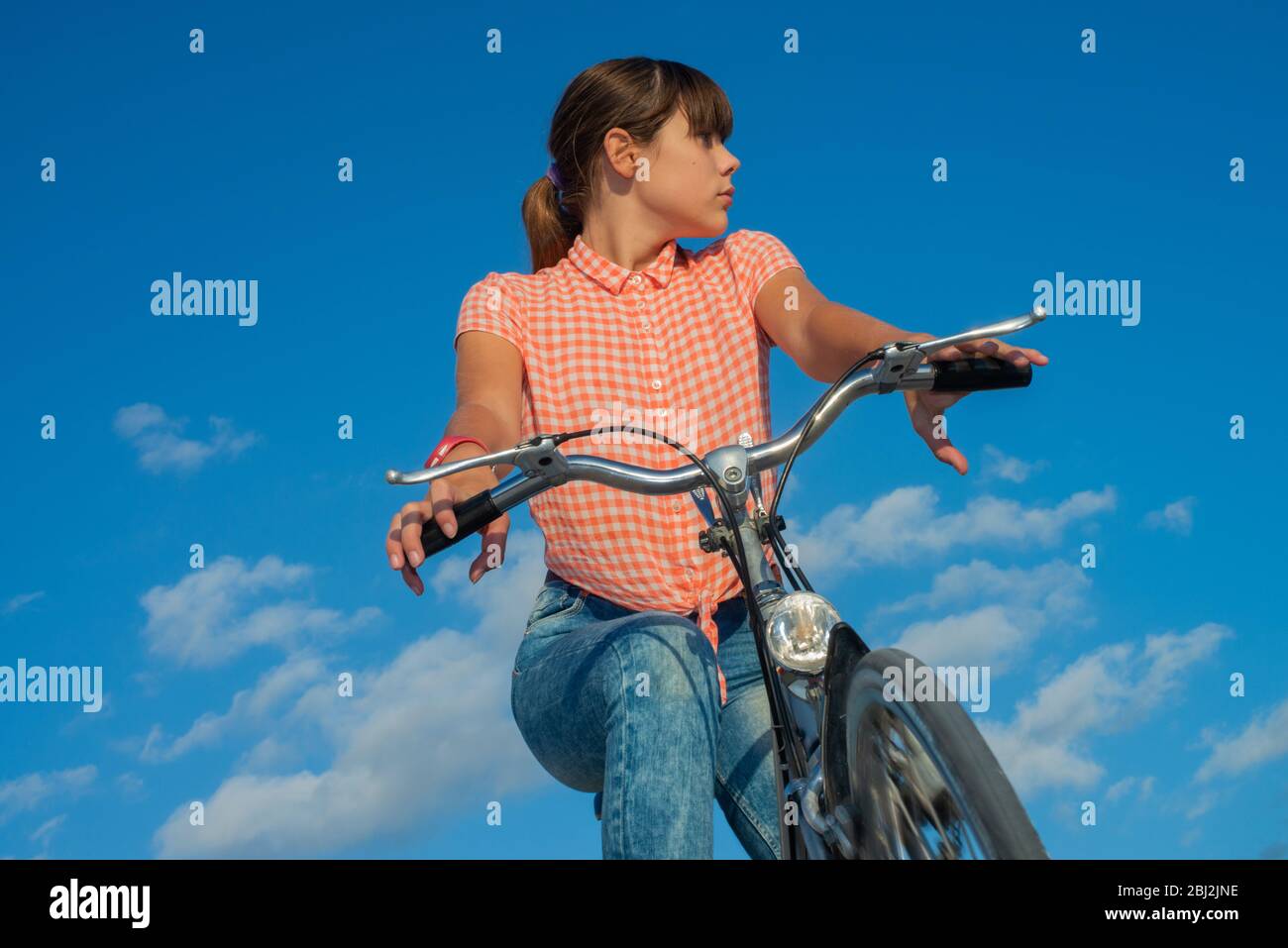 Mädchen fährt Fahrrad mit blauem Himmel Hintergrund Stockfoto