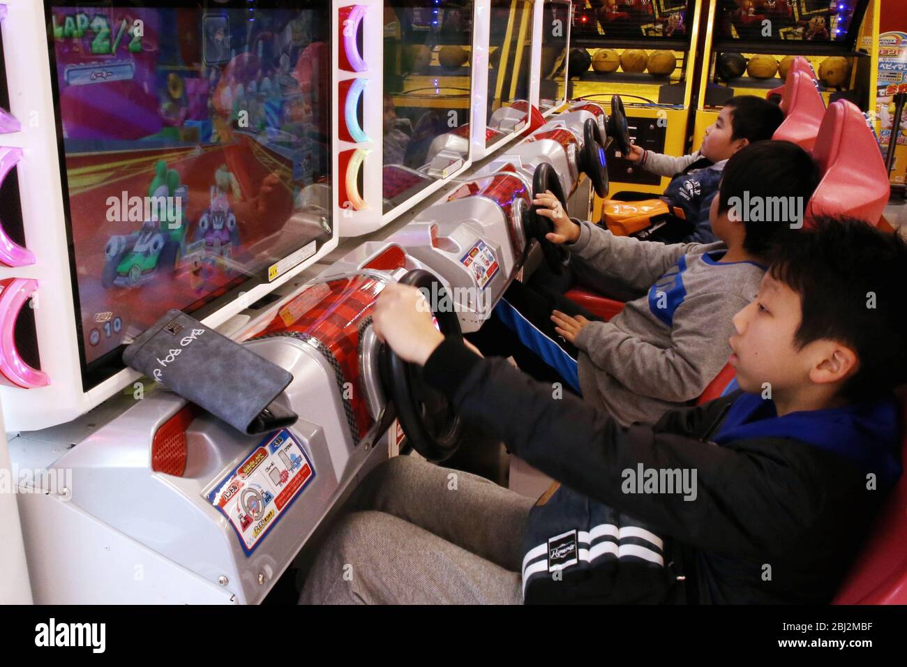 Kinder, die Mario Kart Arcade GP DX-Spiel im Tatio Game Center in Tokio spielen.vor drei Jahren bekam die achte große Folge der Mario Kart-Serie einen großen Geschwindigkeitsschub, als Nintendo Mario Kart 8 Deluxe auf dem Nintendo Switch herausbrachte. Stockfoto