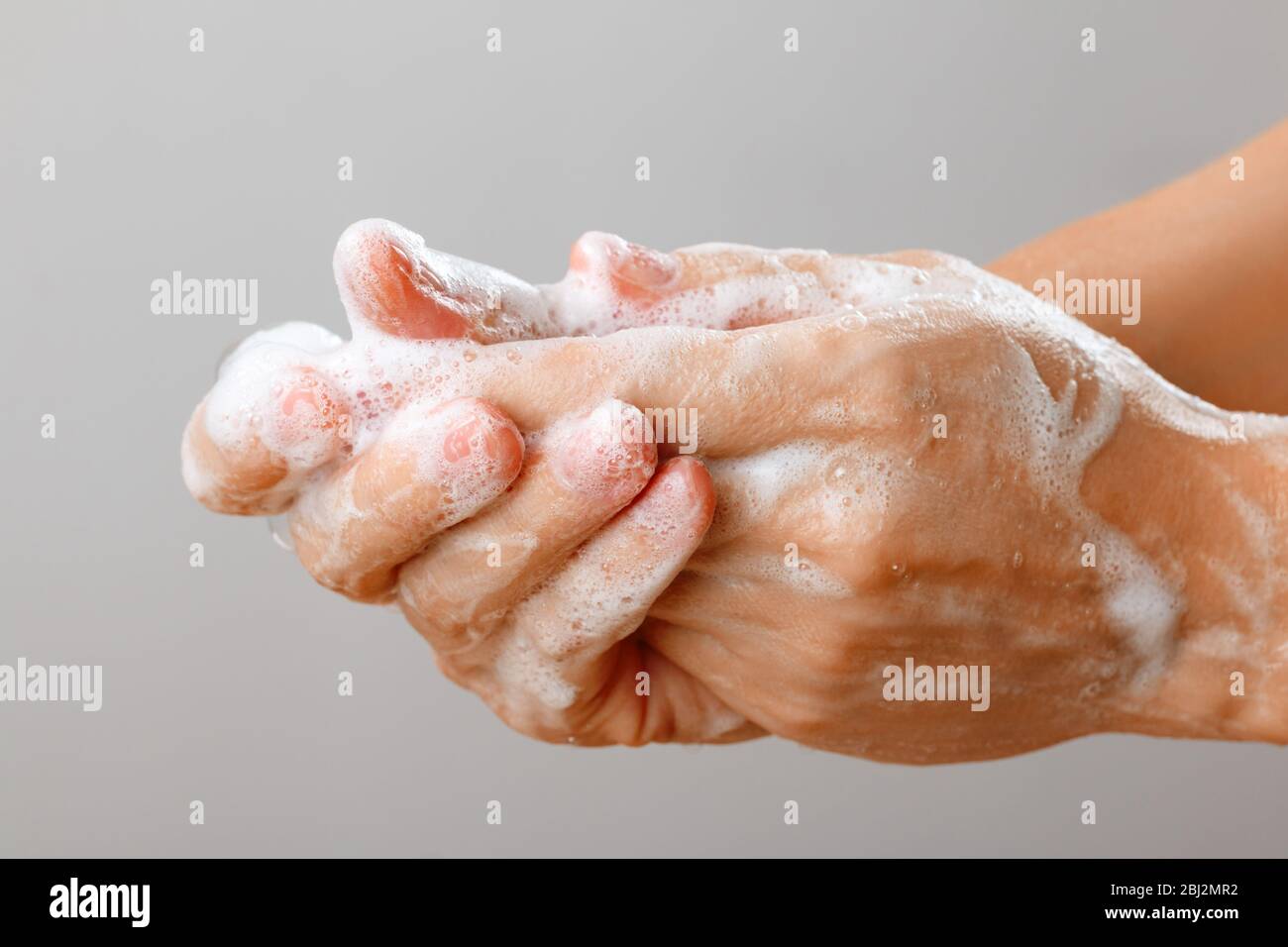 Nahaufnahme der Frau, die Hände mit Seife auf grauem Hintergrund wäscht. Hygienische Prävention der Desinfektion des Coronavirus-Virus. Stockfoto
