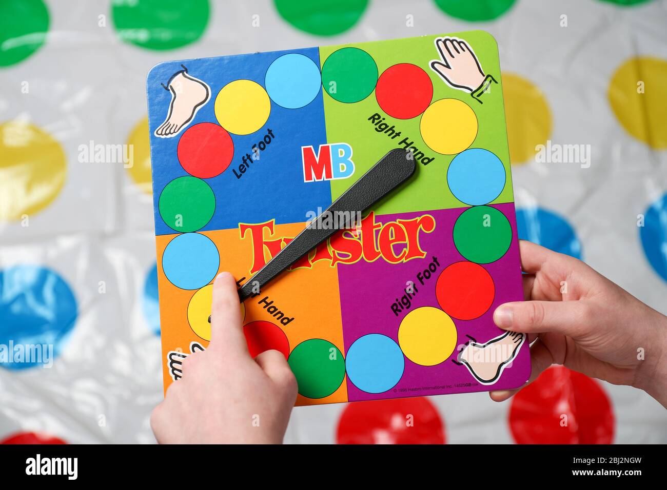 Ein Junge dreht die Twister Spiel Spinner vor seinem auf der Matte gehen. Stockfoto