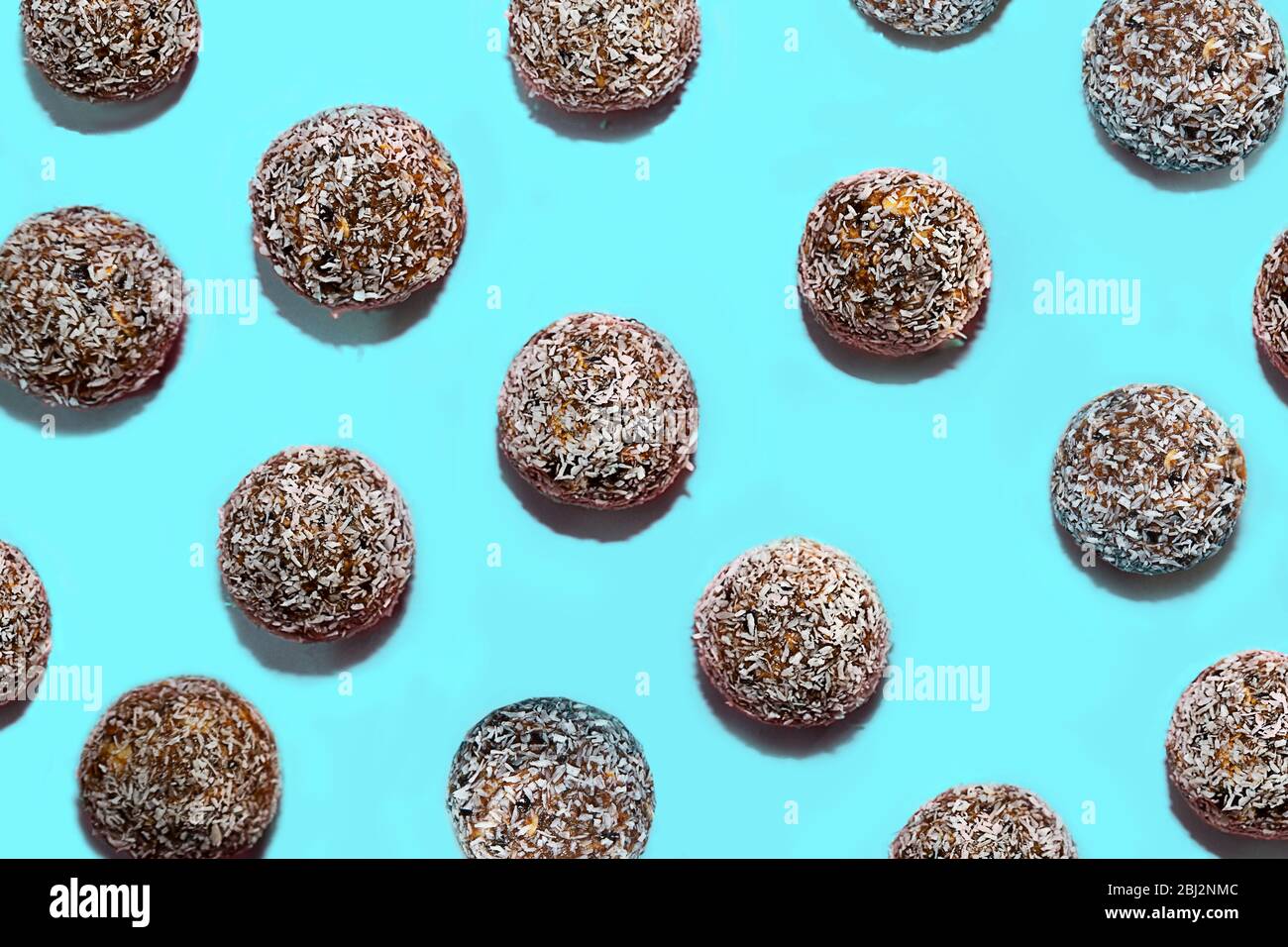 Muster aus Energiebällen mit Hafer, Schokolade und Kokosnuss auf blauem mintgrünem Hintergrund. Gesunde vegane und rohe Ernährung. Richtige Ernährung Konzept. Selektiver Fokus. Kopierbereich. Stockfoto