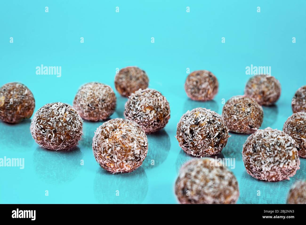 Energiekugeln mit Hafer, Schokolade und Kokosnuss auf blaugrünem Minzgrund. Gesunde vegane und rohe Ernährung. Richtige Ernährung Konzept. Selektiver Fokus. Kopierbereich. Stockfoto