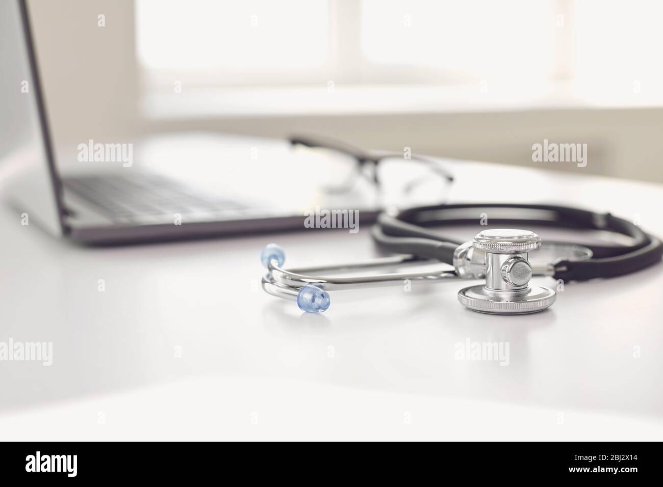 Online Arzt Anruf Konzept. Telemedizin. Stethoskop und Laptop auf einem weißen Tisch. Stockfoto
