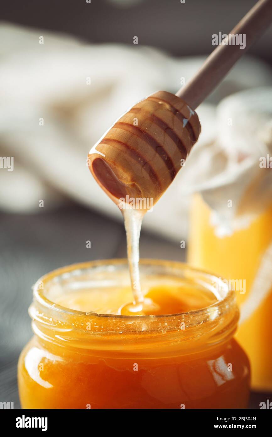 Honighintergrund. Süßer Honig im Glasbecher auf Holzgrund. Stockfoto
