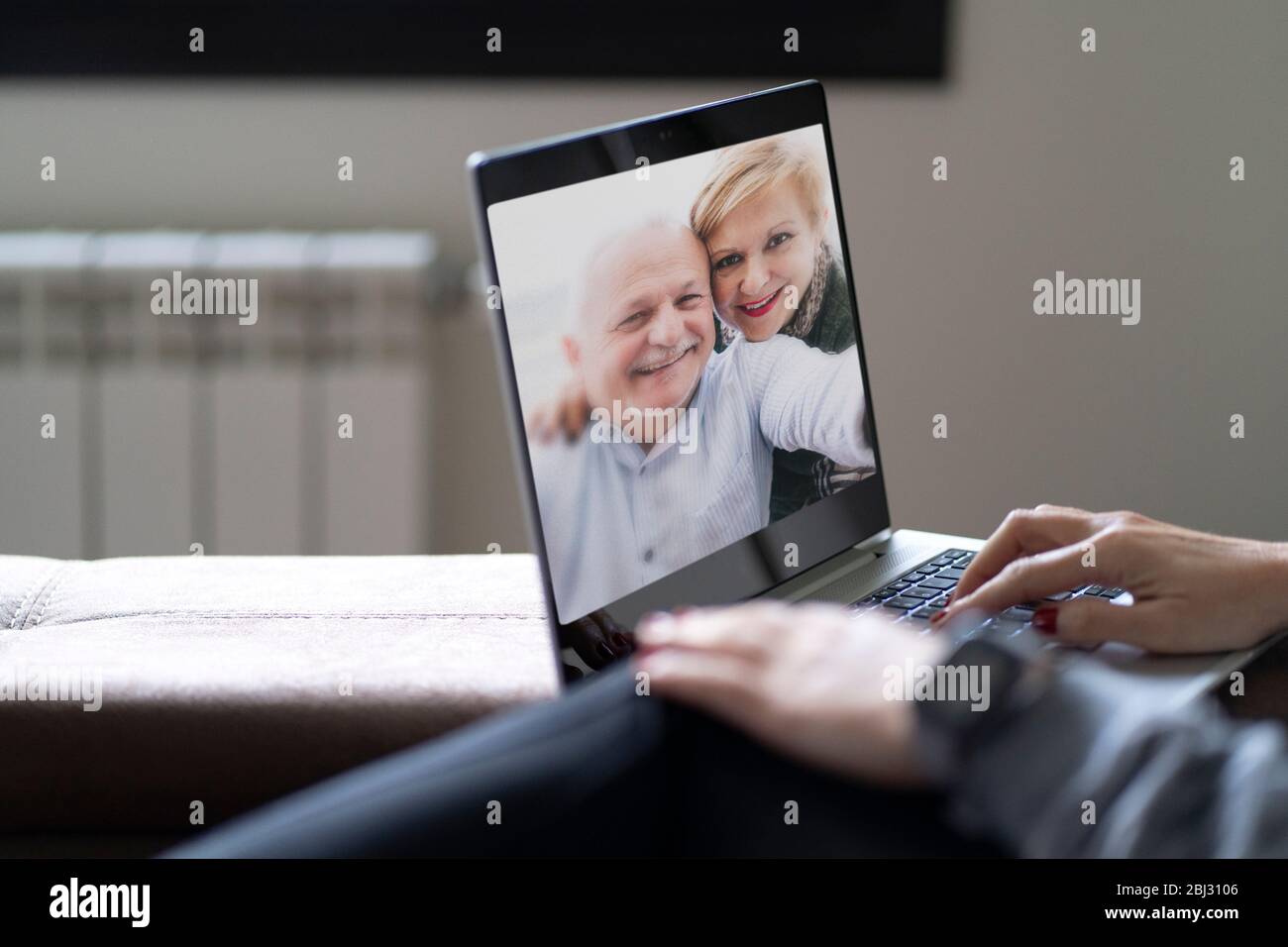 Rückansicht einer Frau, die in einem Videoanruf mit ihren Eltern in einem Online-Briefing spricht, eine Frau, die eine Webcam-Konferenz mit ihrer Familie auf einem modernen Lapt hat Stockfoto