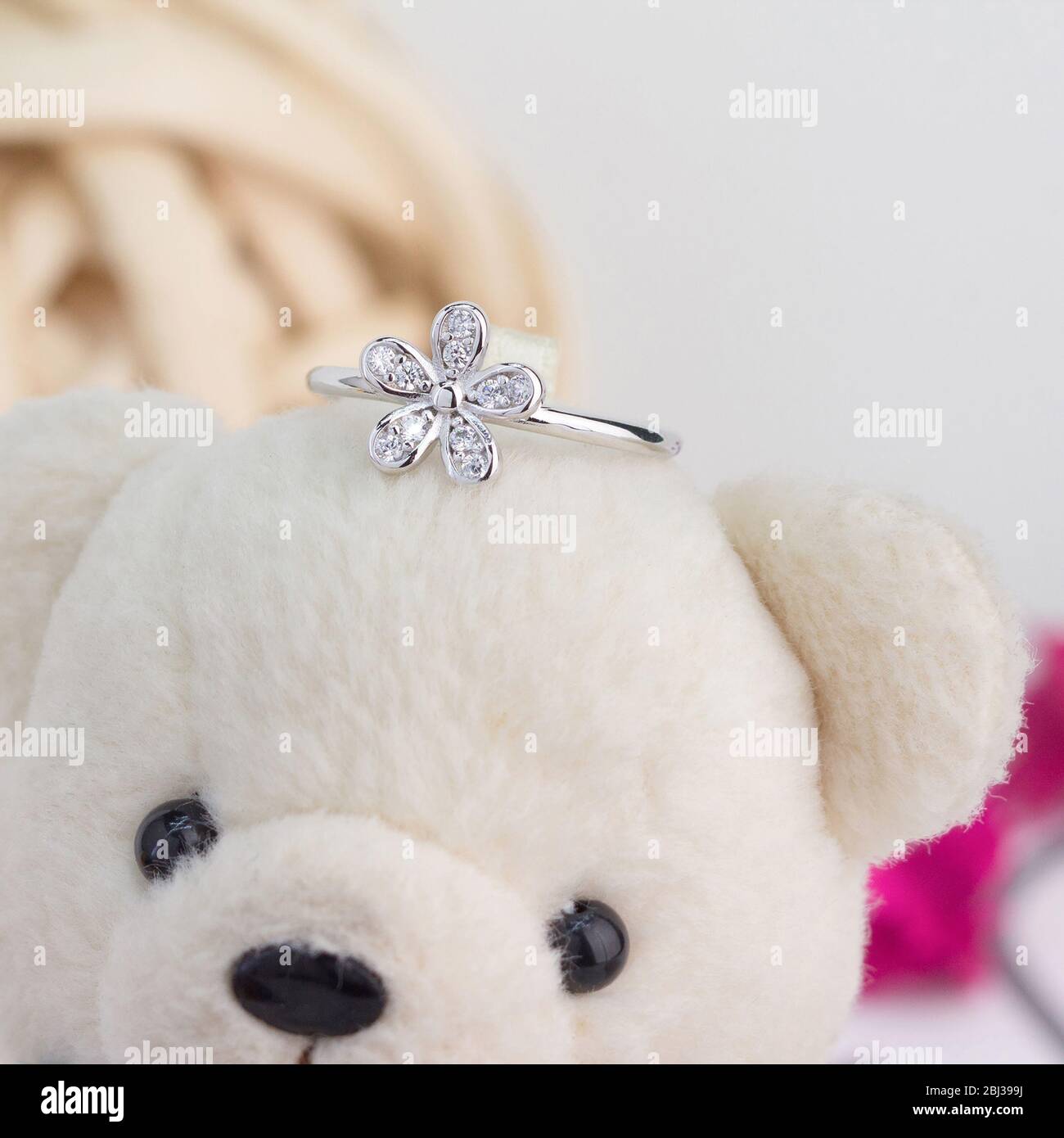 Niedlicher silberner Ring in der Blumenform mit Diamanten verziert Display auf Spielzeug Bär Stockfoto