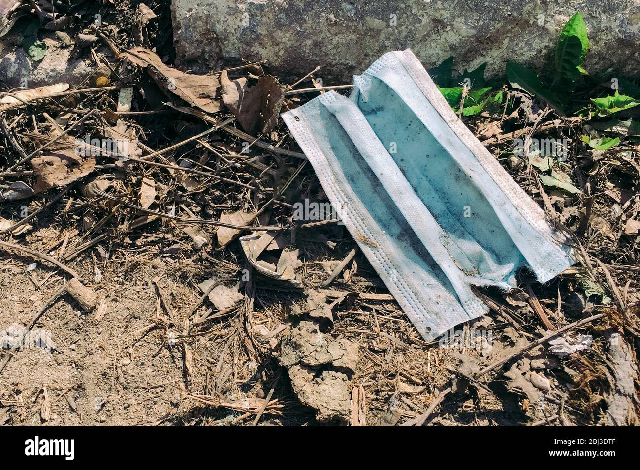 Eine gebrauchte medizinische Gesichtsmaske, die während der Covid-19-Pandemie auf den Boden geworfen wurde. Konzept der Umweltverschmutzung Stockfoto