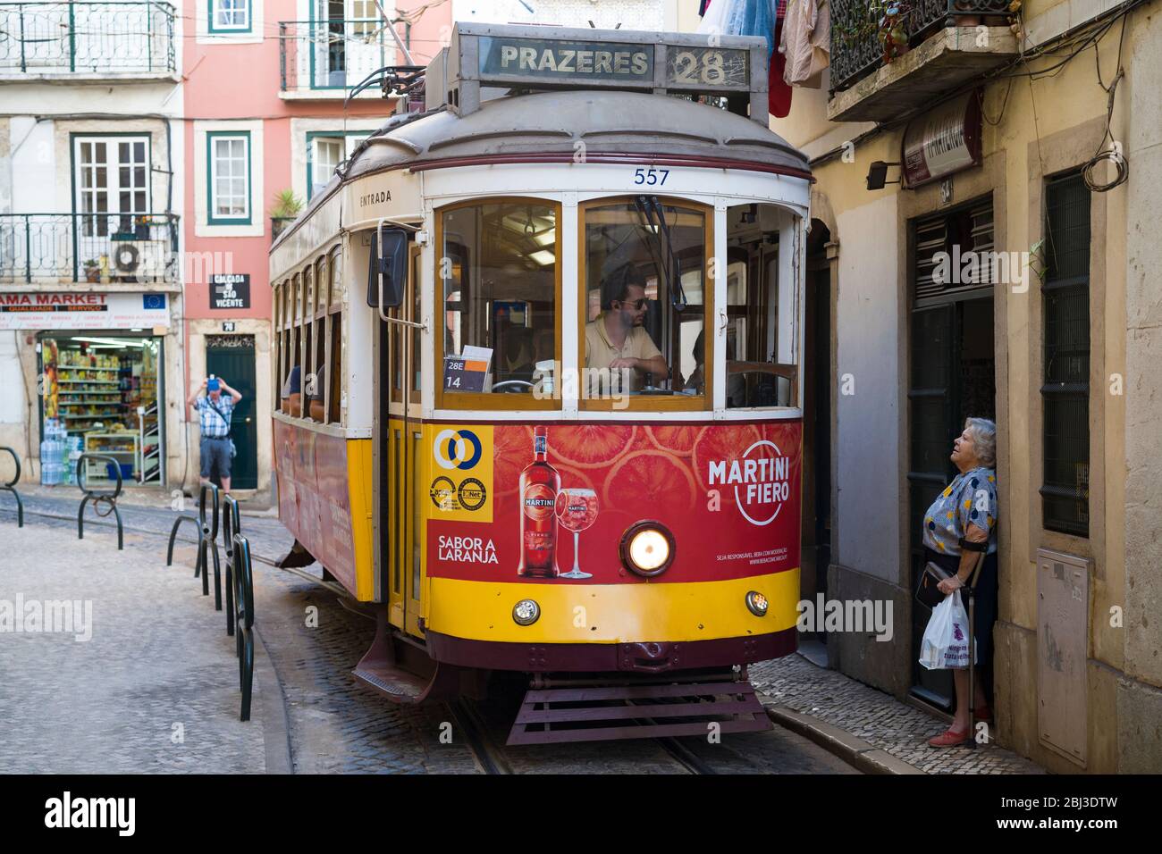 Historische Nr. 28 Tram mit Einheimischen und Touristen-Fahrer im Gespräch mit der lokalen Frau in Alfama Bezirk von Lissabon, Portugal Stockfoto