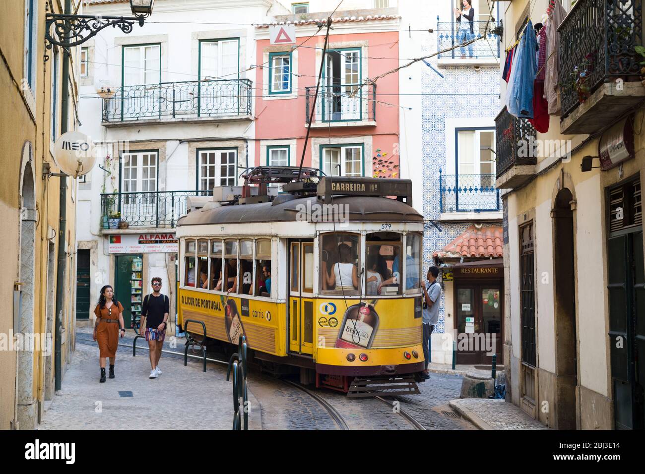 Historische berühmte Straßenbahn Nummer 28, die Einheimische und Touristen auf Tramgleisen entlang der Einkaufsstraße im Alfama-Viertel, Lissabon, Portugal, transportiert Stockfoto