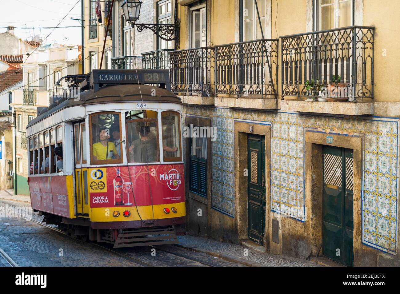 Historische berühmte Straßenbahn Nummer 28, die Einheimische und Touristen auf Tramgleisen auf einem steilen Hügel in Lissabon, Portugal, transportiert Stockfoto