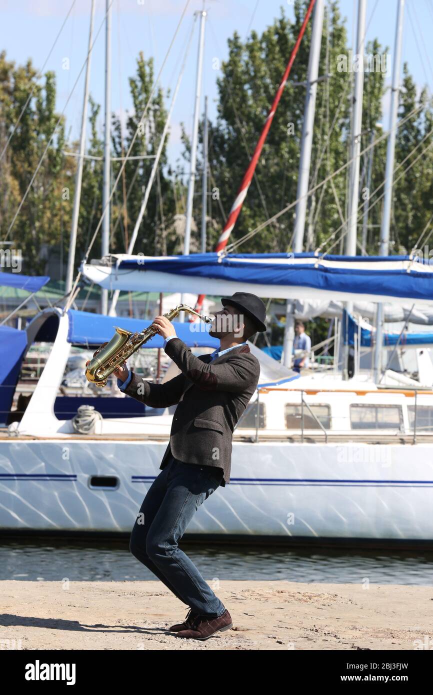 Schöner Mann spielt Saxophon vor der Yacht Stockfoto