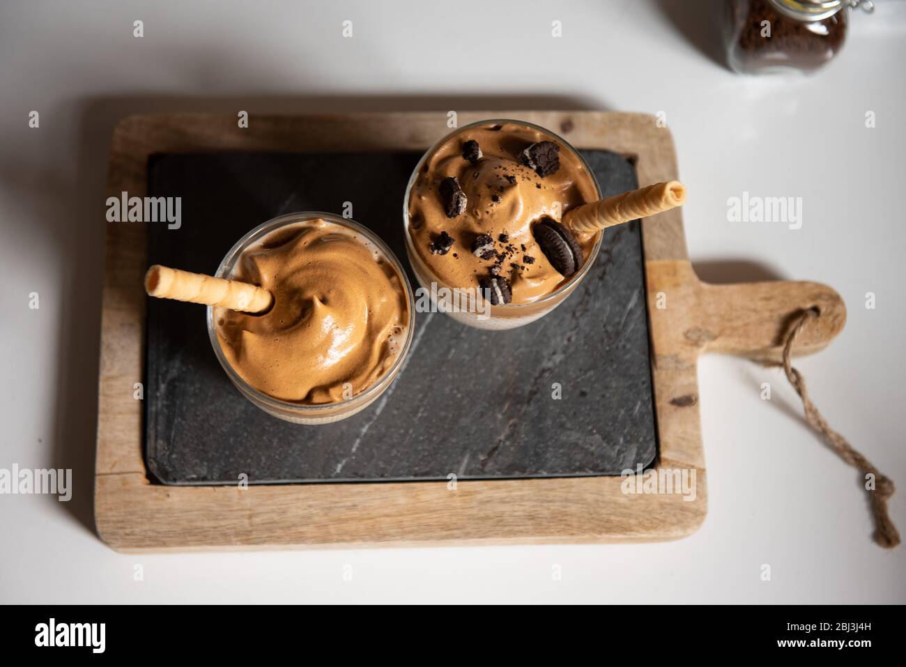 Dalgona Kaffee, ein trendiges Getränk. Zwei Gläser Dalgona Kaffee auf einem Holzbrett Stockfoto
