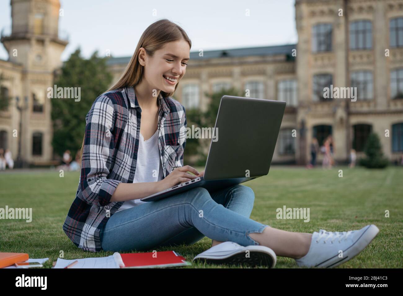 Attraktive lächelnde Frau mit Laptop-Computer, Eingabe auf der Tastatur, Online-Arbeit. Erfolgreiche Studenten studieren, Sprache lernen Stockfoto