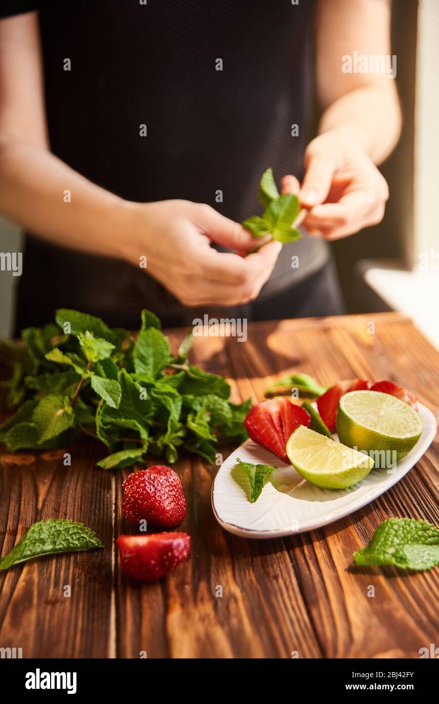 Limette Erdbeere Minze Zutaten für die Herstellung von Limonade auf weißem Teller auf Holztisch Stockfoto
