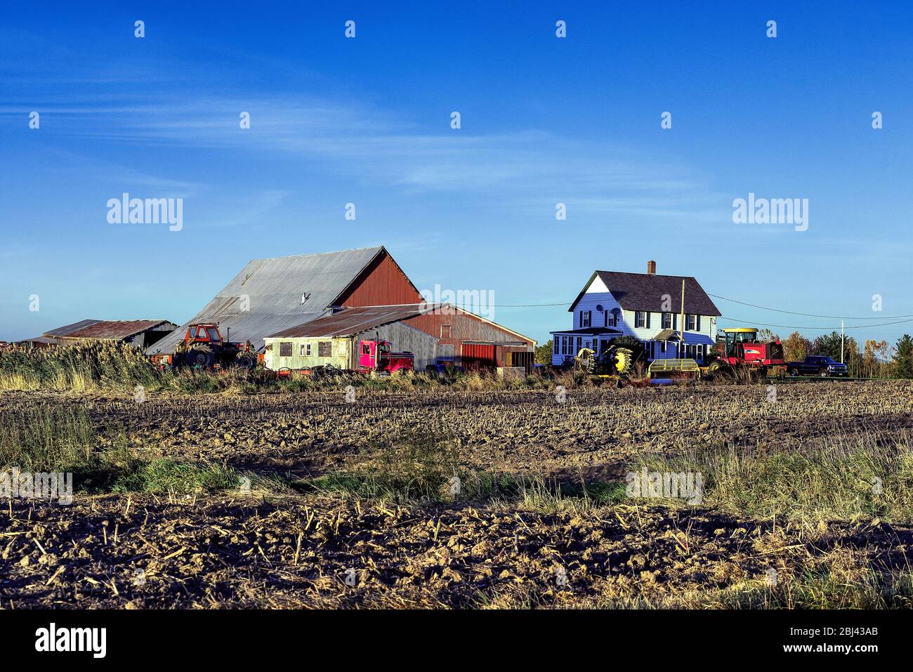 Bunte Scheune mit Traktoren und Bauernhaus in Vermont. Stockfoto