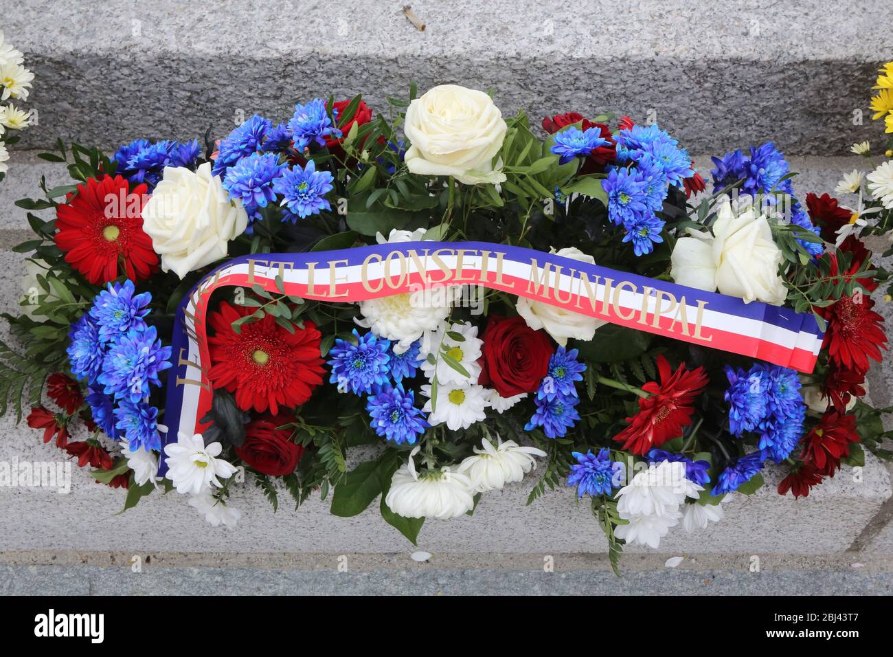 Gerbe de fleurs déposée au pied'un Monument aux morts lors de la cérémonie du 11 novembre. Stockfoto