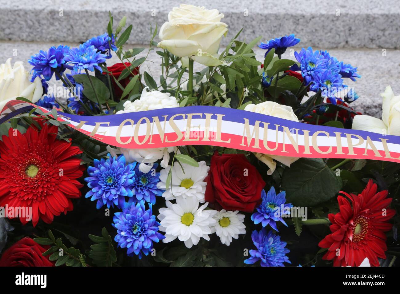 Gerbe de fleurs déposée au pied'un Monument aux morts lors de la cérémonie du 11 novembre. Stockfoto