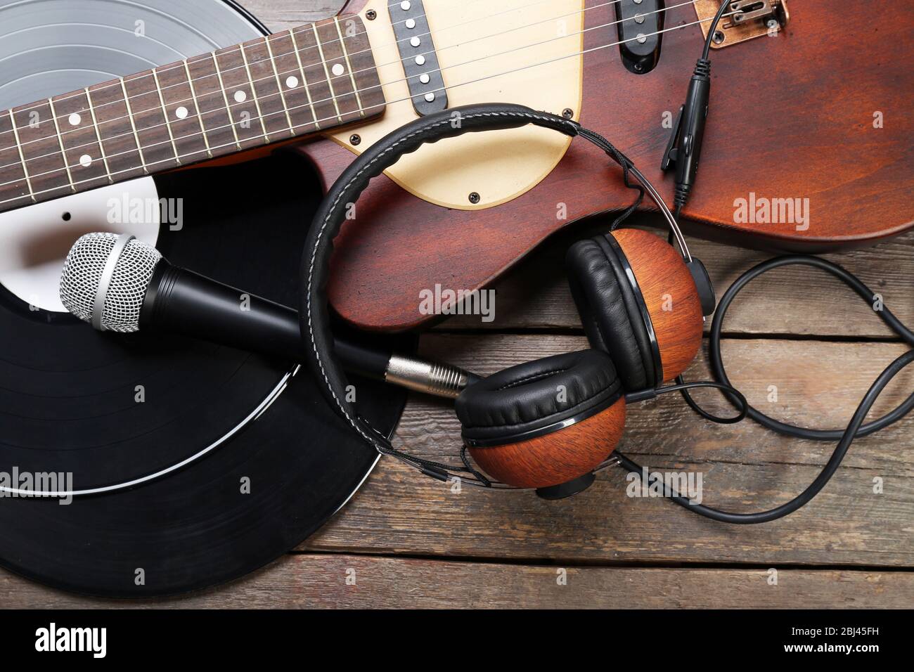 EGitarre und Kopfhörer mit Mikrofon und Vinyl auf Holzhintergrund Stockfotografie Alamy