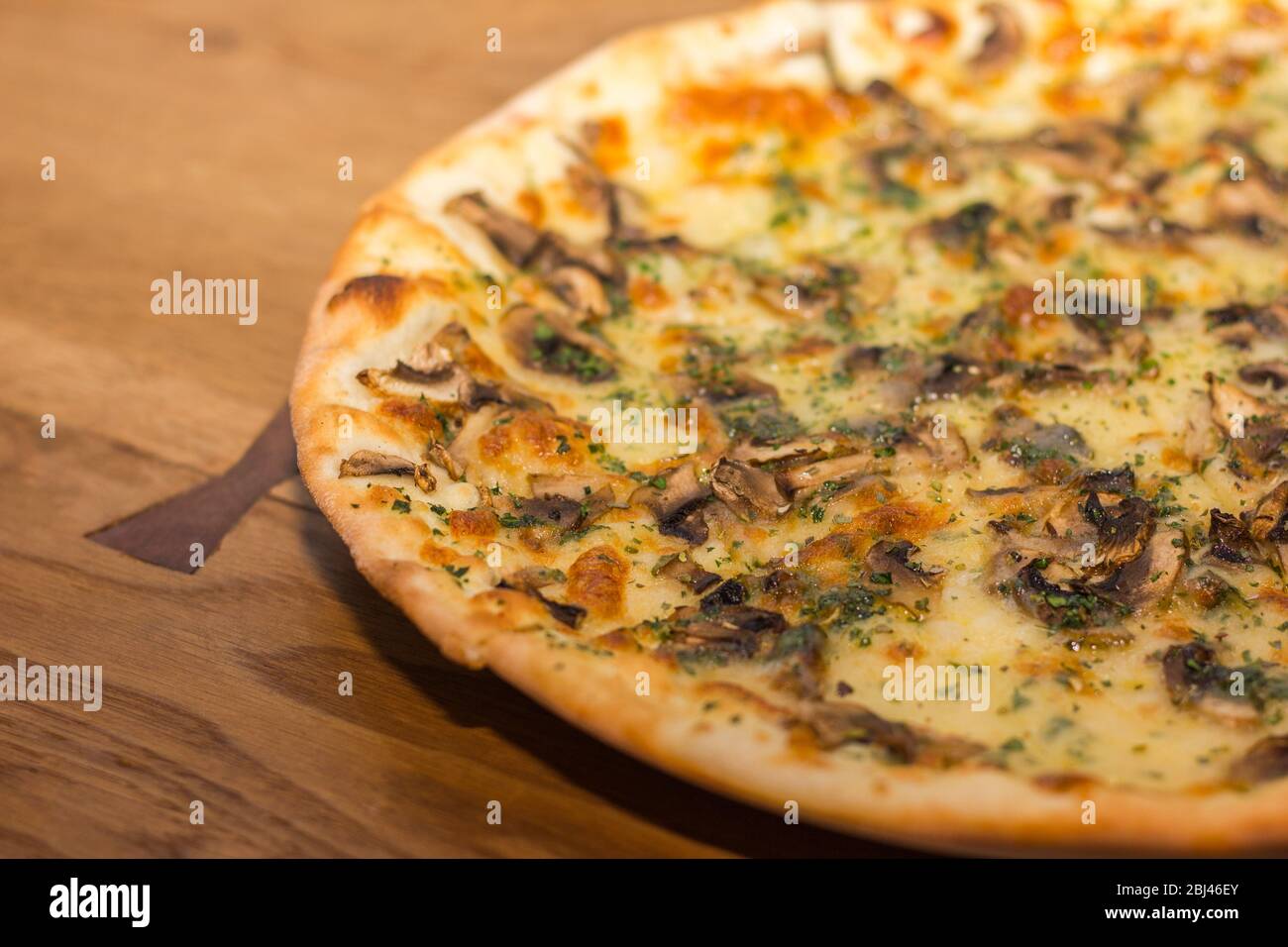 Pizza mit Pilzen und Käse wird mit trockenen italienischen Kräutern bestreut Stockfoto