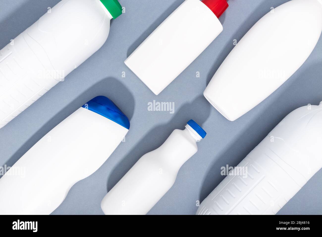 Gruppe von weißen Plastikflaschen auf grauem Hintergrund. Hintergrund Kunststoffrecycling. Draufsicht Stockfoto