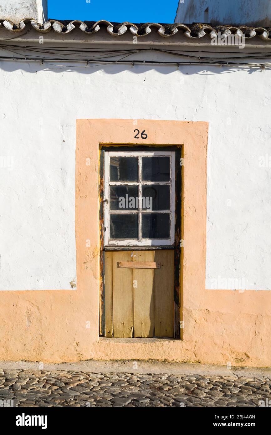 Typisches malerisches Haus mit alter Eingangstür in einer gepflasterten Steinstraße in Evora, Portugal Stockfoto