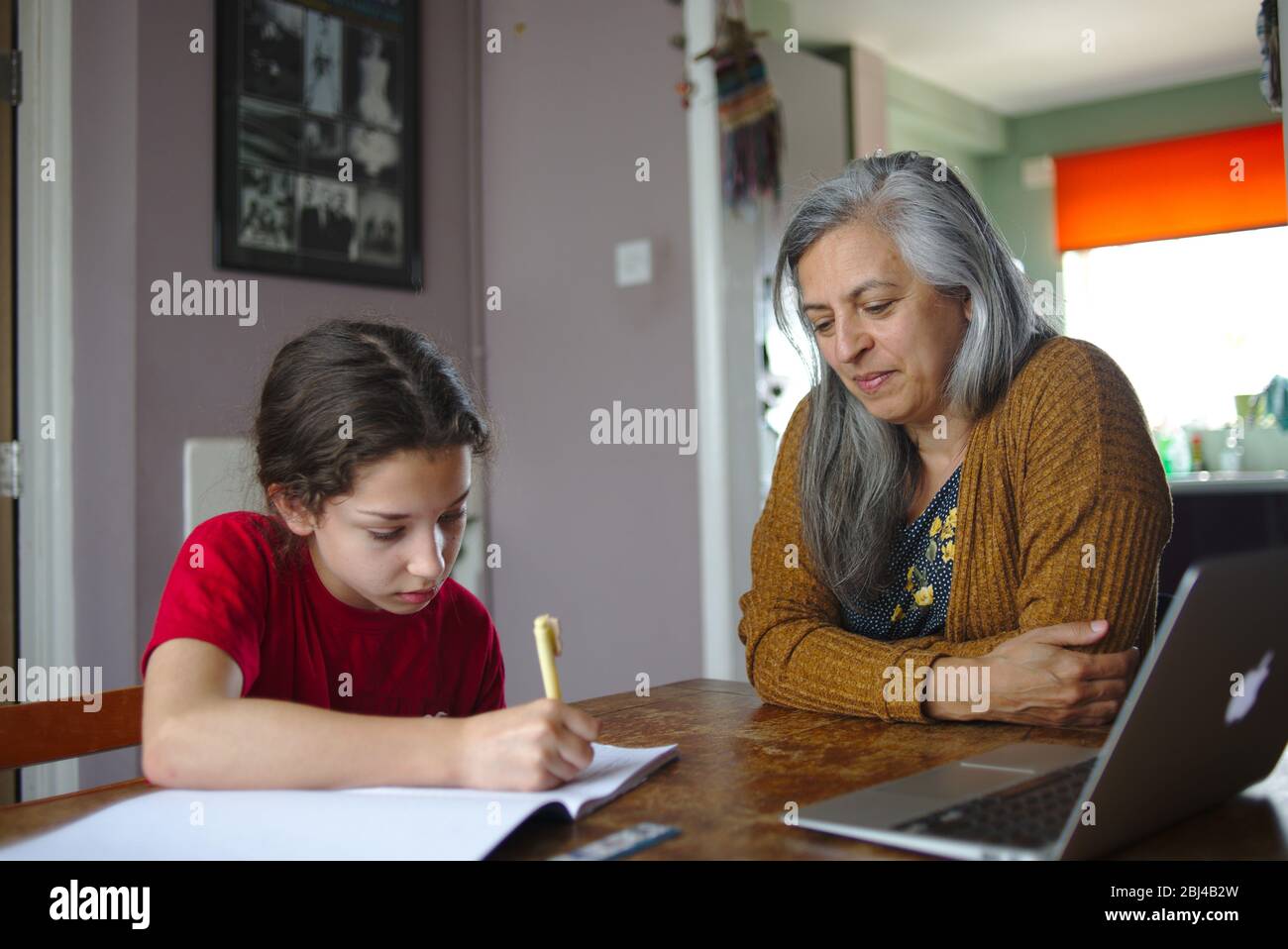 Eltern helfen Kind bei der Schularbeit zu Hause während der Coronavirus-Sperre. April 2020 Großbritannien Stockfoto