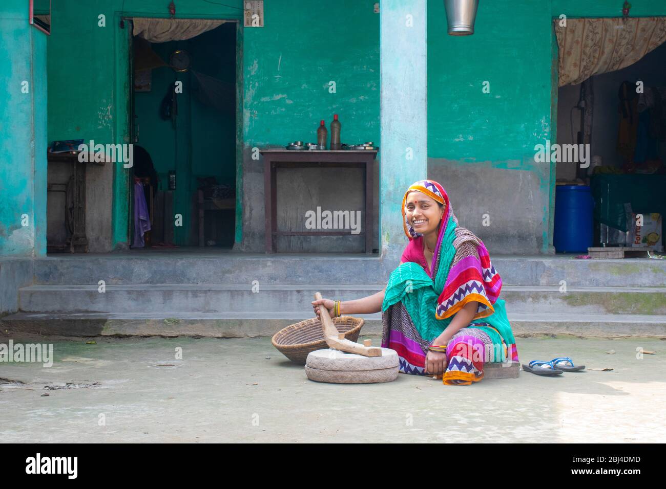 Indische Frau mahlen Mehl in Schleifstein bei ihrem Haus in einem Dorf Stockfoto