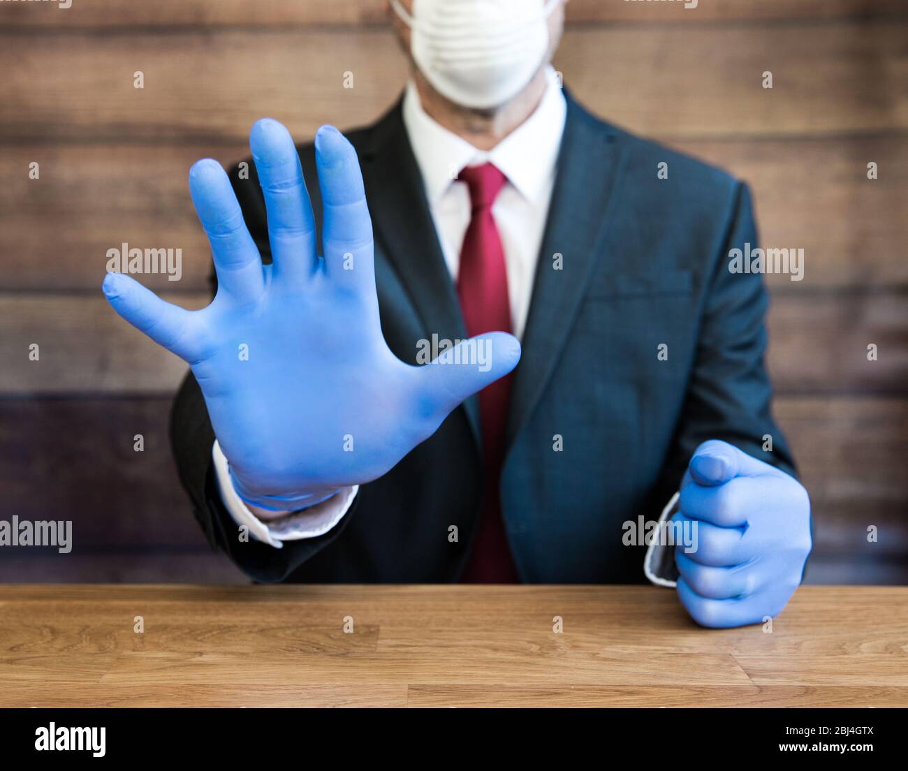 Ein Arzt oder Geschäftsmann trägt psa blaue Handschuhe und Gesichtsmaske während der Coronavirus Pandemie gestikuliert Menschen, weg und soziale Distanz zu bleiben, wenn p Stockfoto