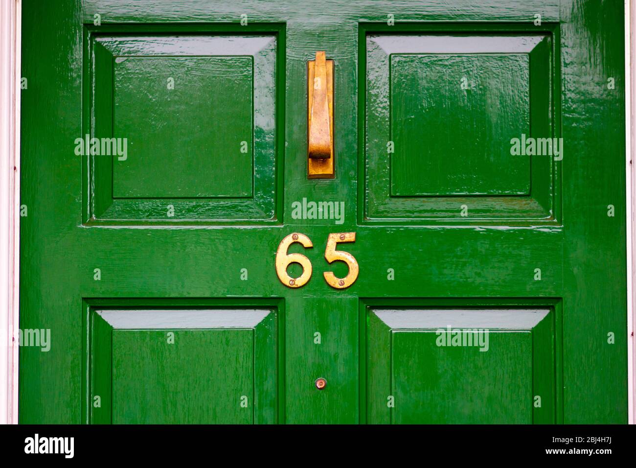 Haus Nummer 65 auf einer grünen Holztür Stockfoto