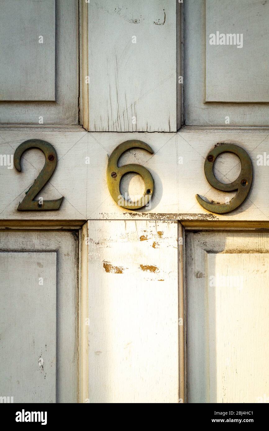 Hausnummer 269 auf einer abgenutzten weißen Tür Stockfoto