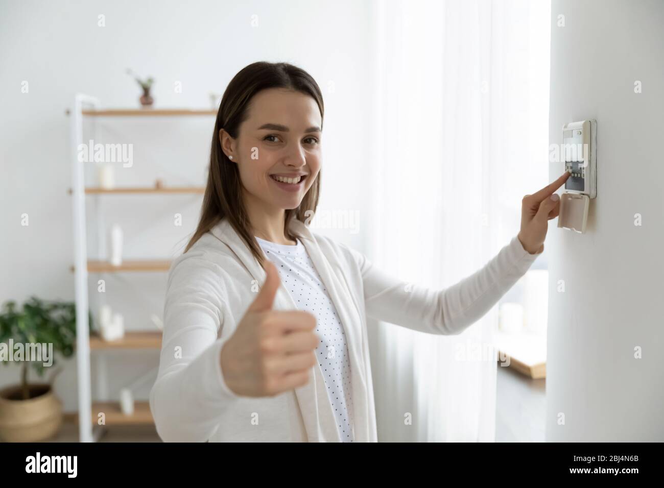 Lächelnde Frau verwenden Smart Home Bedienfeld System Stockfoto