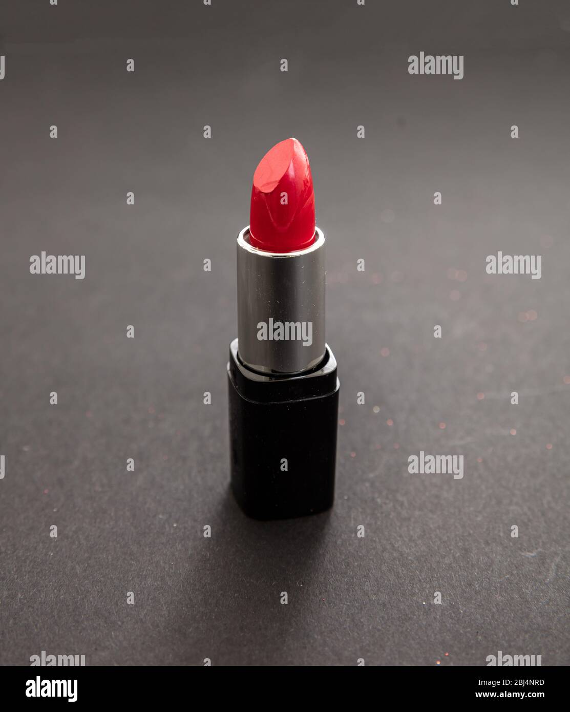 Lippstick rote Farbe vor schwarzem Hintergrund, Nahansicht. Leuchtend roter Lippenglanz, Kosmetik, Makeup-Konzept Stockfoto