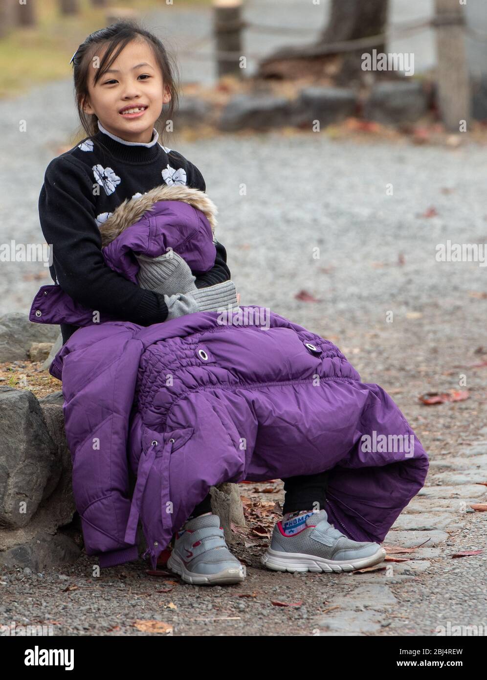 Ein kleines japanisches Mädchen, das eine kurze Pause vom Gehen nimmt. Arashiyama, Kyoto, Japan Stockfoto