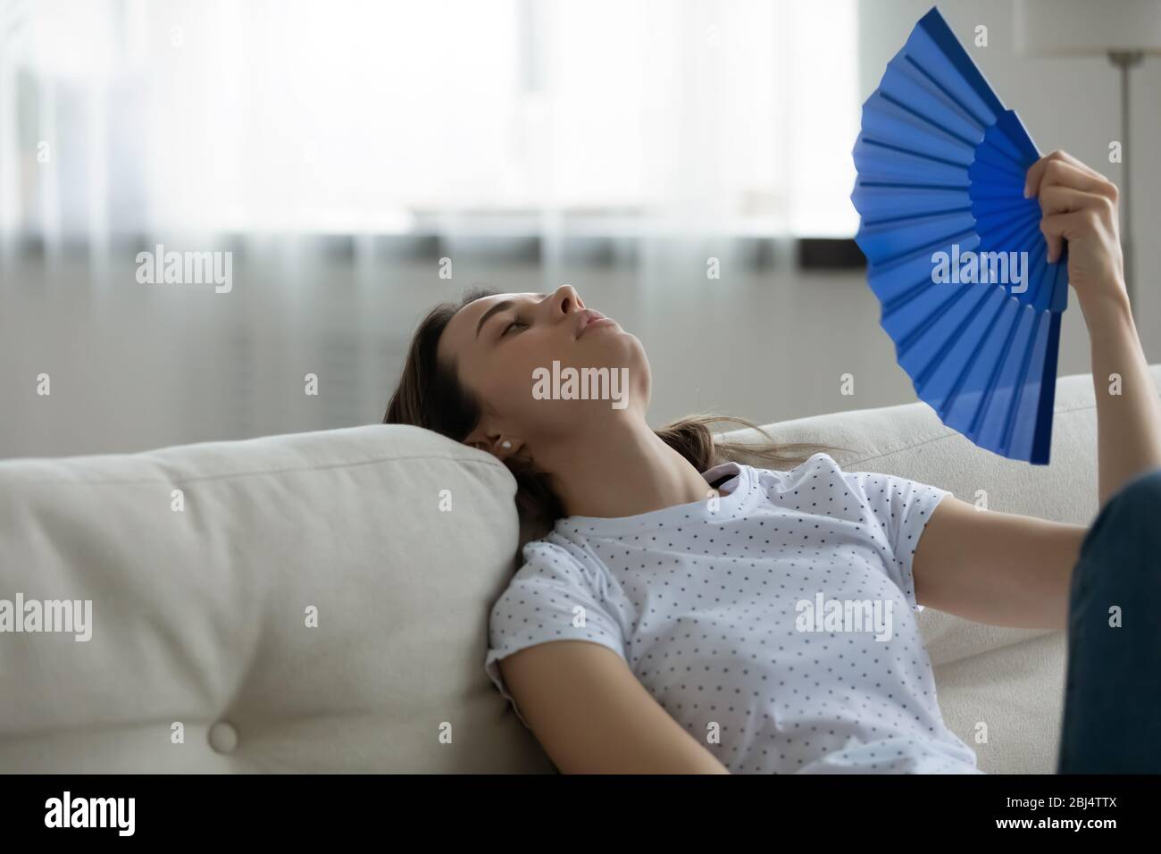 Unwell junge Frau entspannen winken mit Handventilator Stockfoto