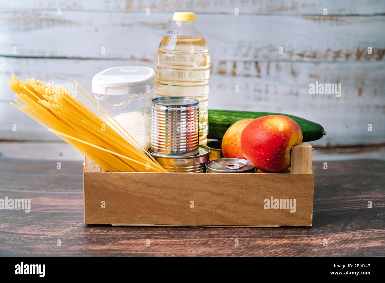 Lebensmittel. Krise Lebensmittel Box Lager für Coronavirus Quarantäne Isolationszeit in Holz Hintergrund. Verschiedene Lebensmittel in Aluminiumdosen, Reis, Nudeln, Öl Stockfoto