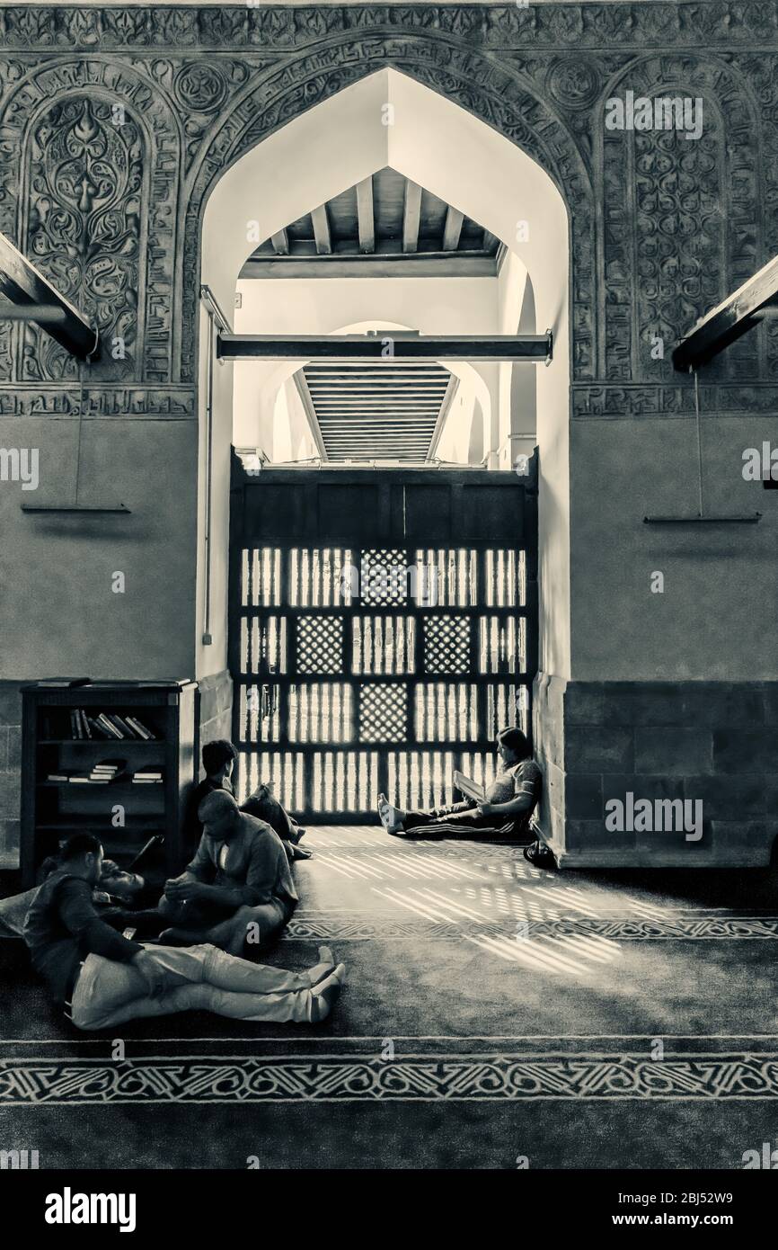 Islamische Studenten studieren im diffusen Licht eines Maschrabiya, in einem Torbogen der Al Azhar Moschee Stockfoto