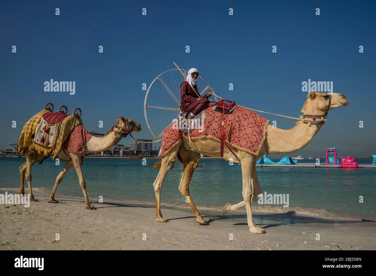Ein Beduinenmann lächelt, als er vor Ain Dubai vorbeifährt, dem größten Riesenrad der Welt am Jumeirah Beach in Dubai. Stockfoto