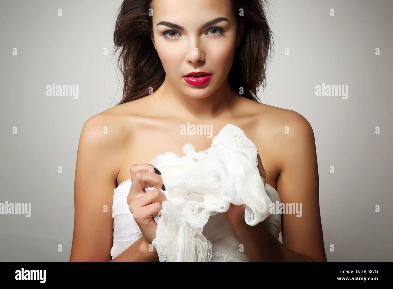 Junge schöne Frau, hält Gaze, auf grauem Hintergrund Stockfoto