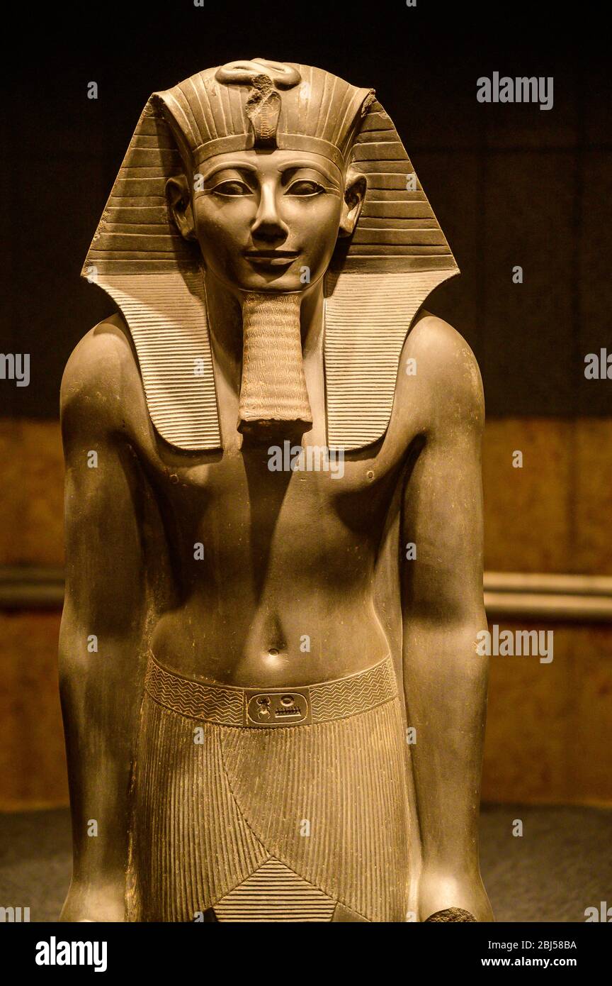 Statue von König Thutmosis III., der den Nemes-Kopfschmuck mit schützenden Uraen, falschem Bart und kunstvollem Kilt mit einer Schnalle trägt, die mit seiner Kartusche beschriftet ist Stockfoto