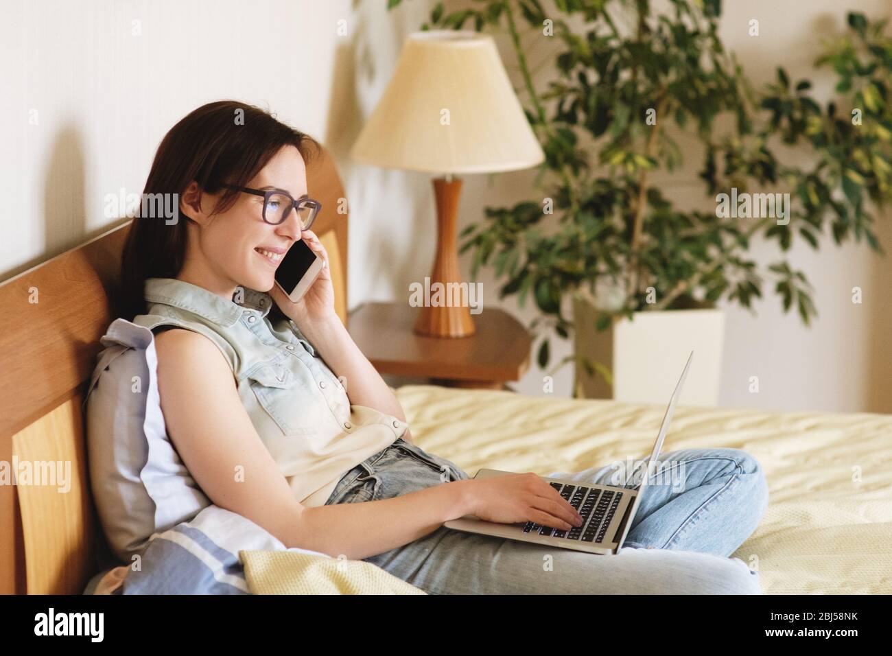 Schöne junge Frau arbeitet auf dem Bett zu Hause. Stockfoto