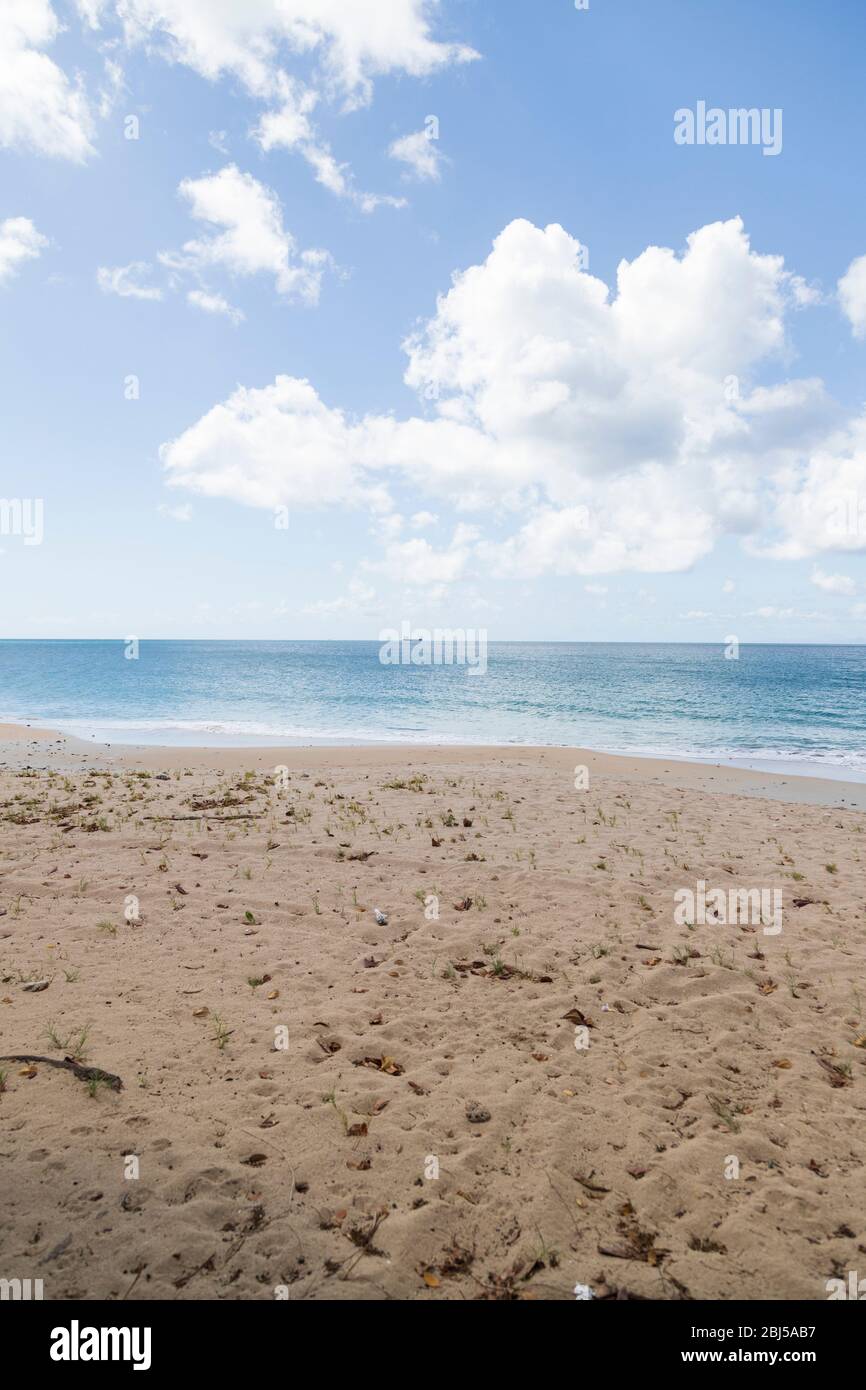 Ein Foto vom Strand in Porträtausrichtung, bestehend hauptsächlich aus Sand und Himmel, mit dem Meer dazwischen schimmernd, das Licht der Sonne reflektierend Stockfoto