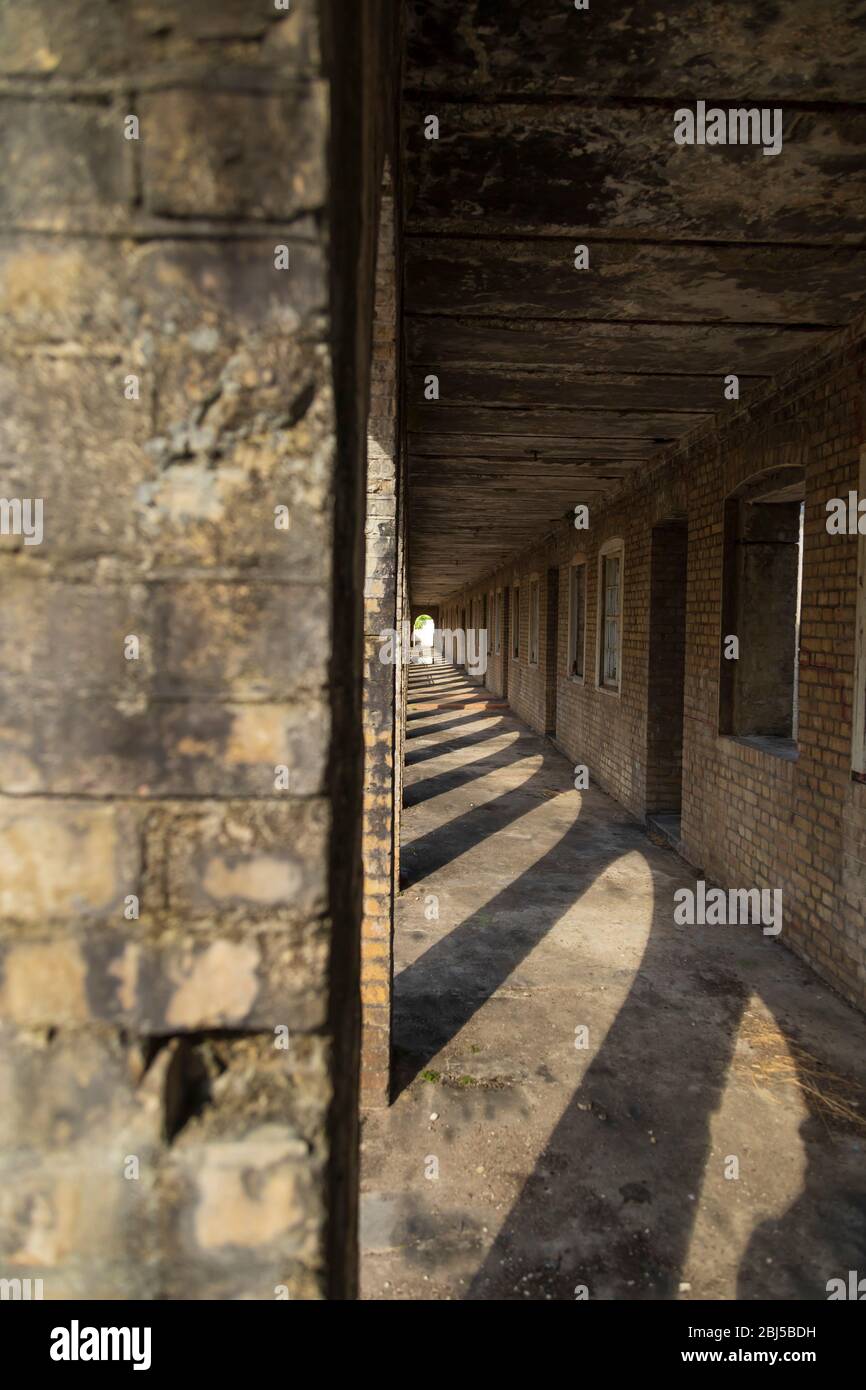Fluchtpunkt von einem Ende des Korridors eines alten Kolonialgebäudes mit den Eingängen zu den Zimmern auf der rechten Seite Stockfoto