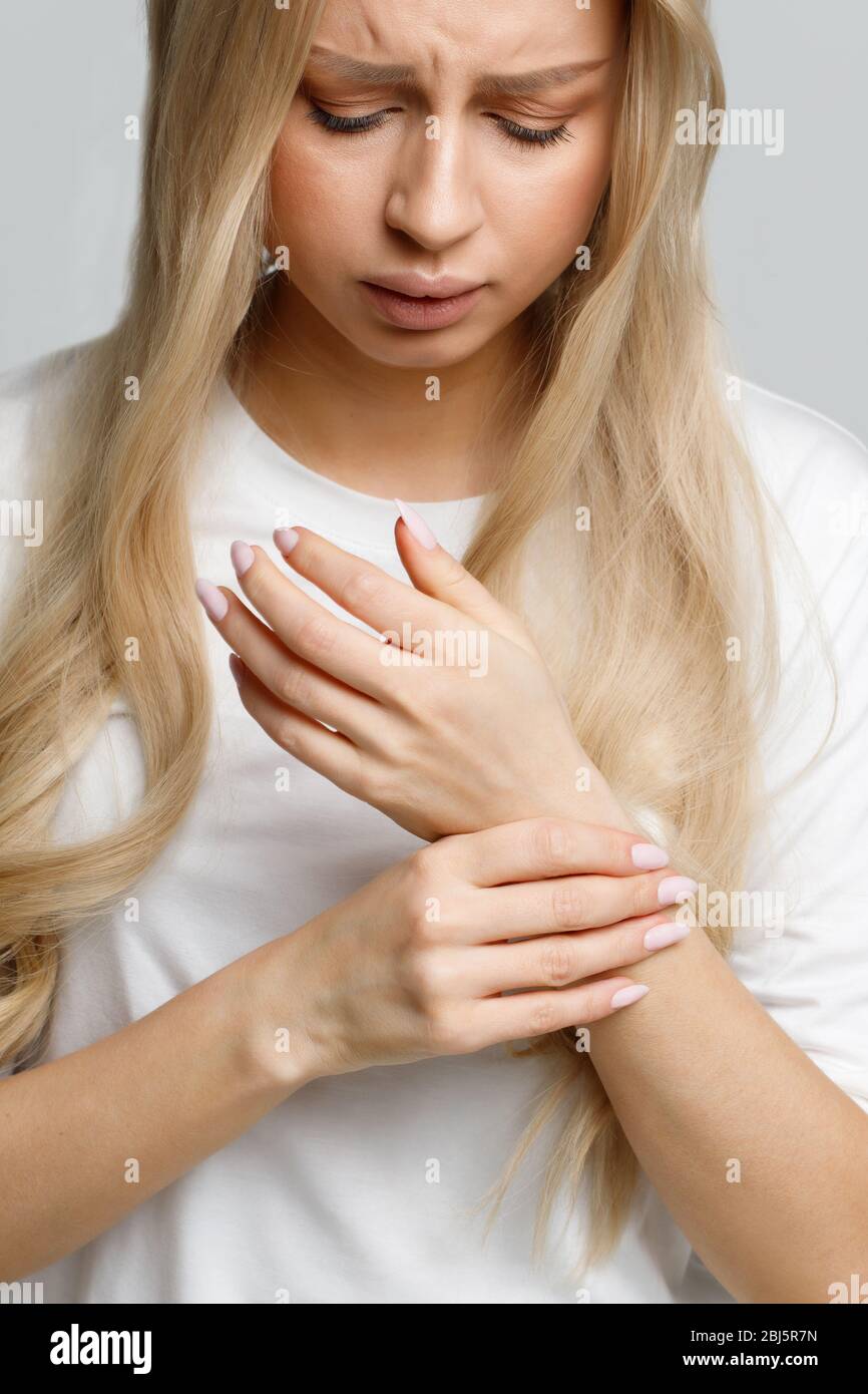 Nahaufnahme Porträt der jungen Frau, die ihr schmerzhaftes Handgelenk hält, verursacht durch längere Arbeit am Computer, Laptop. Karpaltunnelsyndrom, Arthritis, neurol Stockfoto