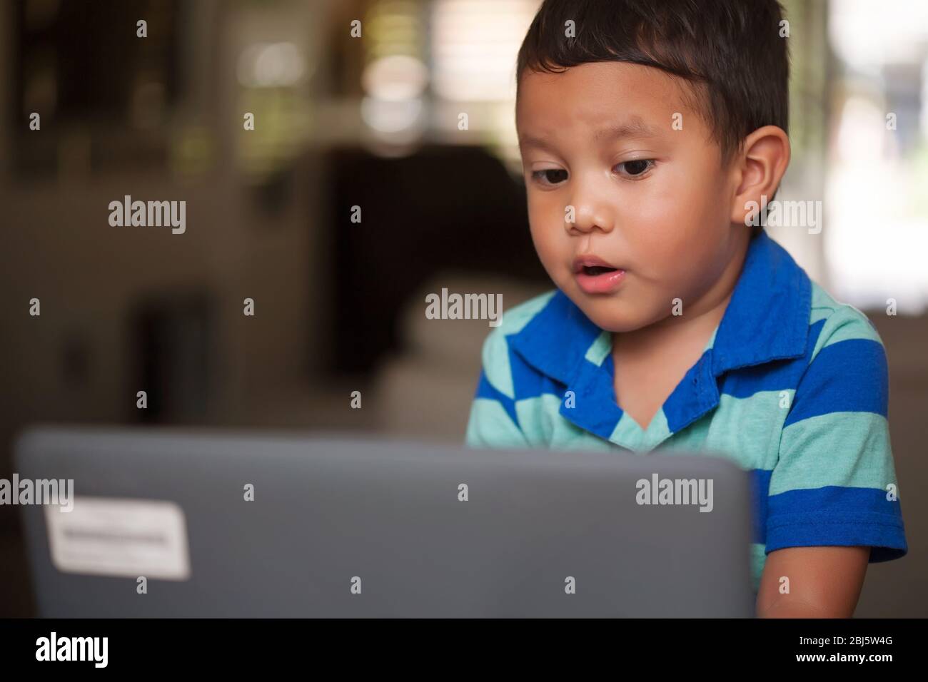 Junger hispanischer Junge, der lernt, Wörter mit einem Laptop und einem speziellen Arbeitsplatz zu Hause auszusprechen. Stockfoto