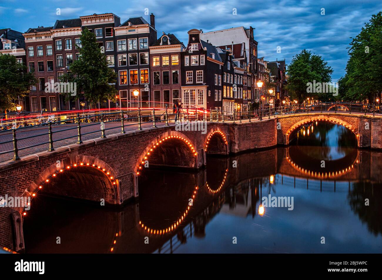 Amsterdam, Niederlande. Sieben Brücken. Keizersgracht und Reguliersgracht Kanäle, beleuchtet mit den kleinen Lichtern, die auf dem Fluss reflektieren Stockfoto