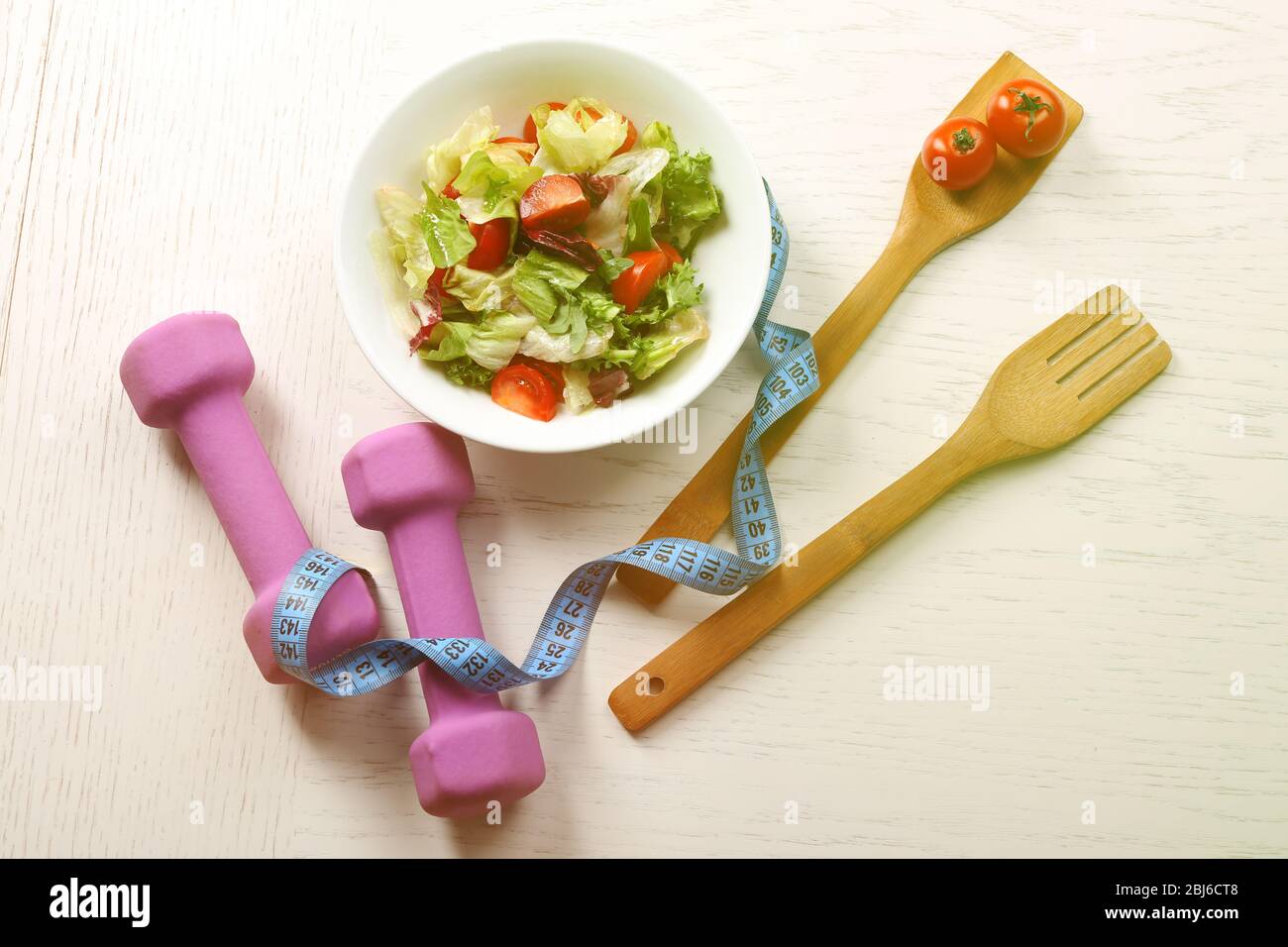 Frischer Gemüsesalat, Hanteln und Maßband. Gesundes Essen und Diät-Konzept Stockfoto