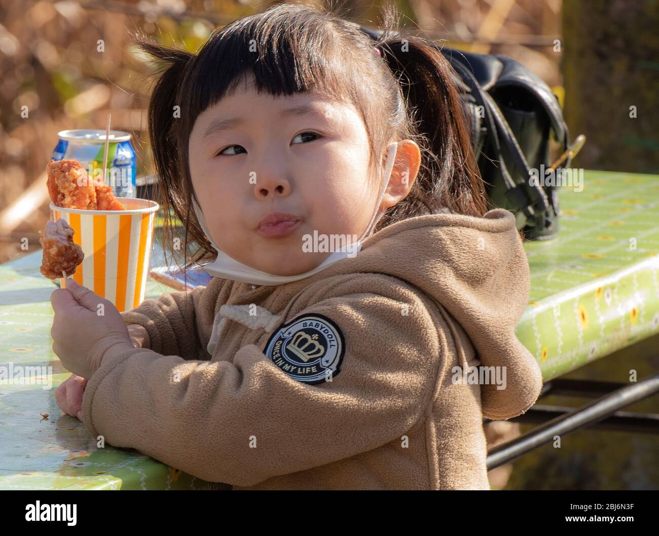 Ein kleines japanisches Mädchen genießt eine Mahlzeit außerhalb des Taito-Schreins im Ueno-Park in Tokio, Japan Stockfoto