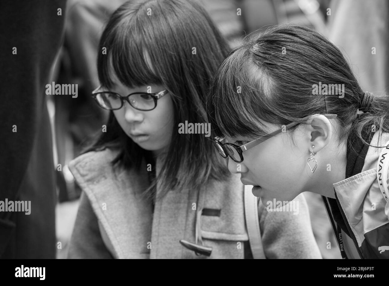Zwei Mädchen, die auf ein Schaufenster eines der vielen Bekleidungs- und Modeläden in Harajuku, Tokio schauen Stockfoto